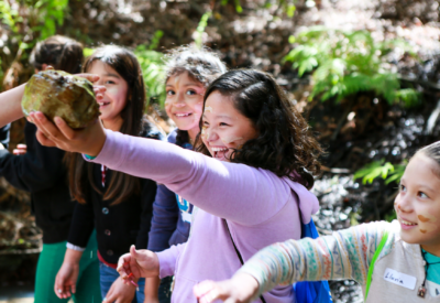 A girl holding up a rock in the forest