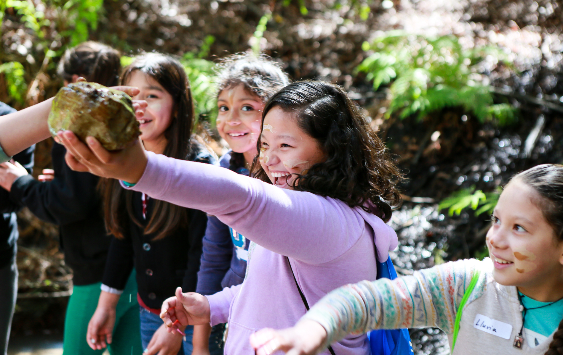 A girl holding up a rock in the forest
