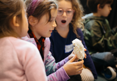 Three girls looking excited while holding an animal skull