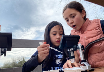 Two girls looking through a microscope