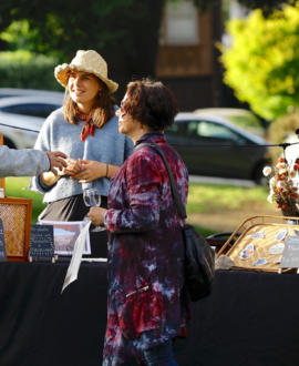 3 people talking to an artist at her outdoor booth
