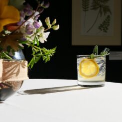 a cocktail on a table with a vase of flowers