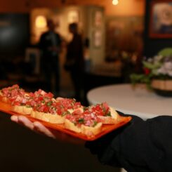 a hand holding a tray of bruschetta