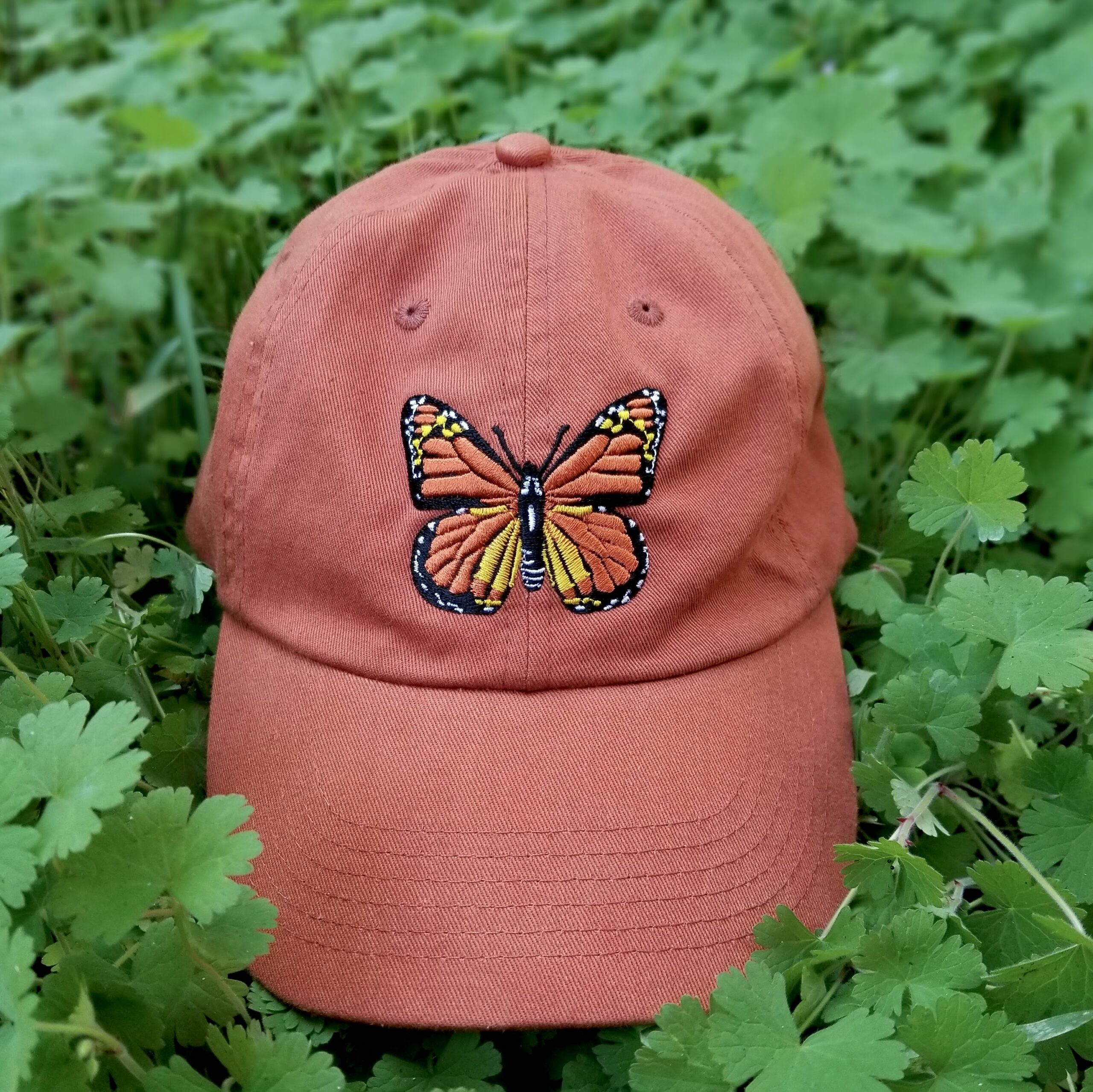 orange baseball hat with embroidered monarch butterfly on the front